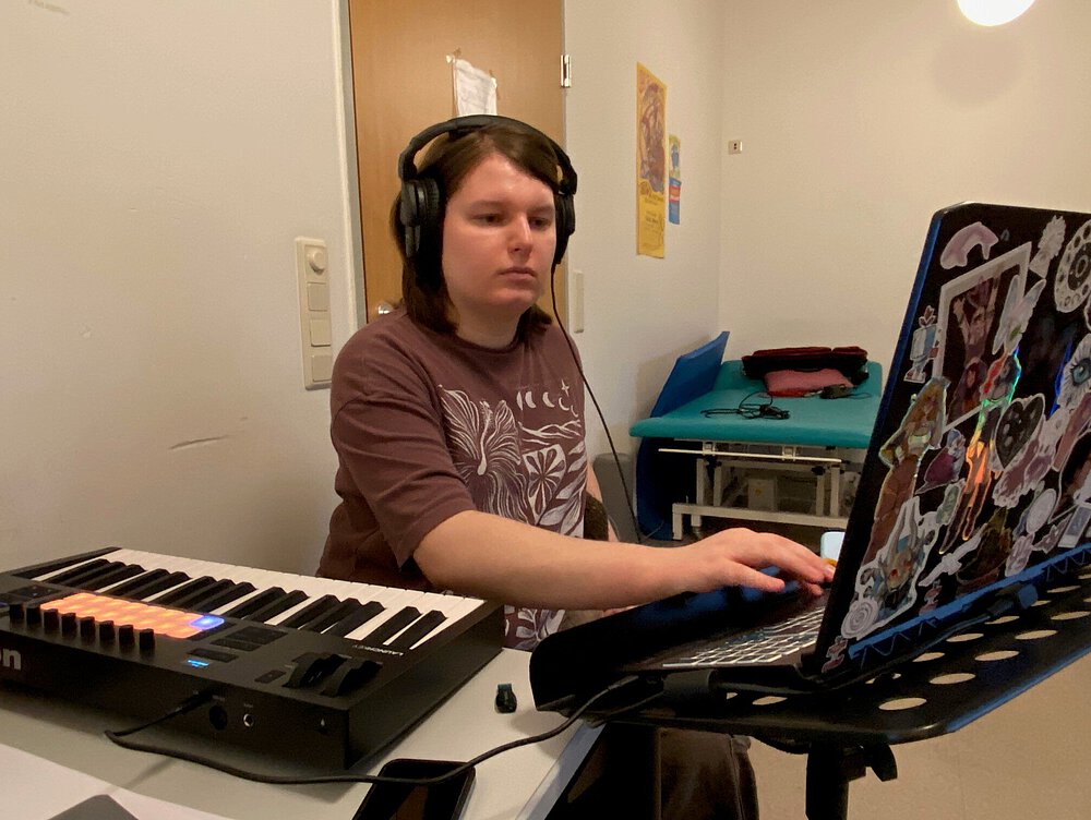 Ein Bandmitglied arbeitet am Keyboard und am PC und hat Kopfhörer auf.