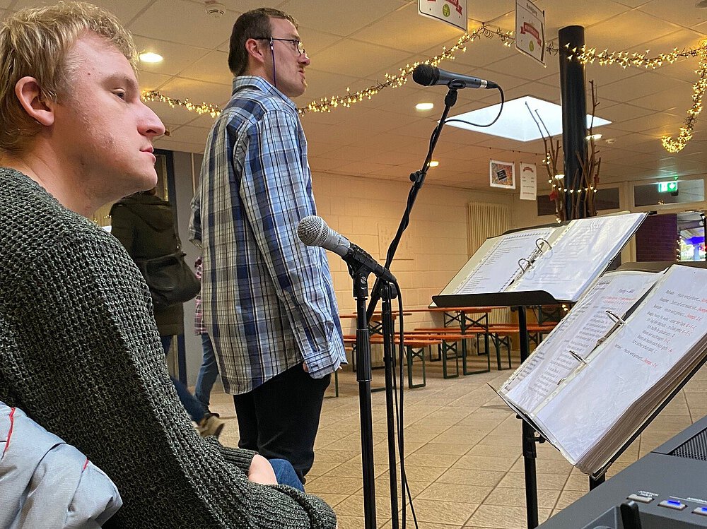 Zwei Bandmitglieder von Tabuwta stehen und sitzem am Mikrofon für die Proben. 